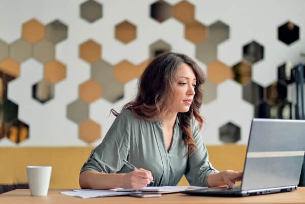 Vrouw is aan het ondernemen en werkt geconcentreerd op haar laptop aan een tafel.