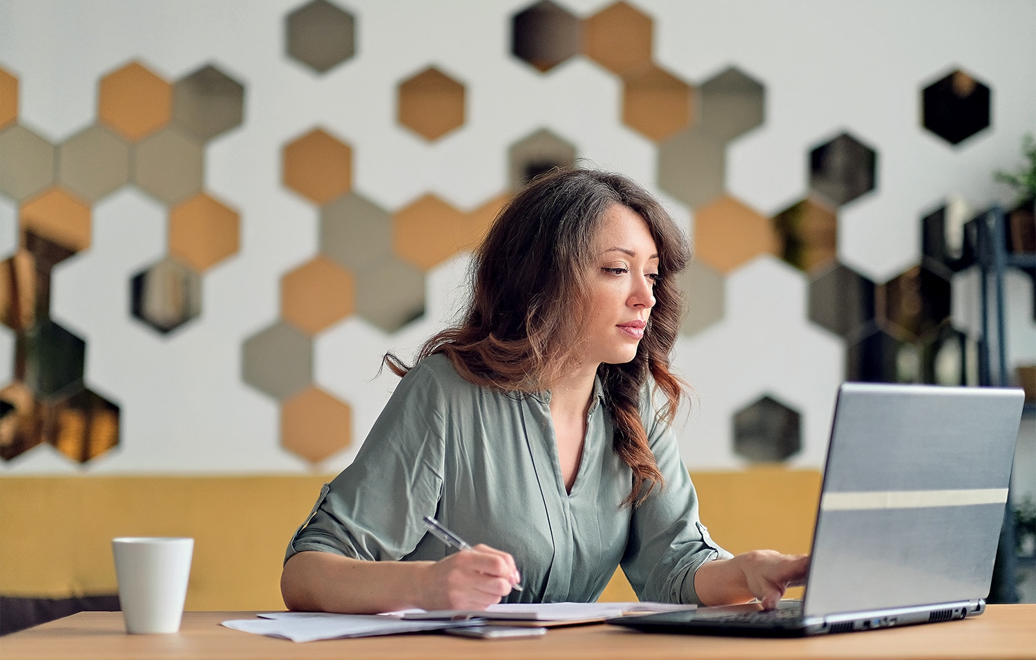 Vrouw is aan het ondernemen en werkt geconcentreerd op haar laptop aan een tafel.